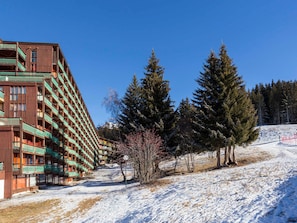 A multi-story hotel with balconies, surrounded by snow-covered ground and evergreen trees.