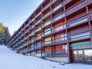 A multi-story hotel with balconies, a sign reading "LES LAUZIÈRES," and a snowy landscape in the background.