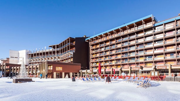 Un hotel amb diverses plantes, zona d'estar a l'exterior i un sòl cobert de neu.