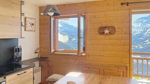 A wooden cabin with a kitchen, dining area, and a window with a mountain view.