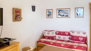 A cozy room with a wooden sofa, a small wooden table, a TV, and a wooden cabinet.