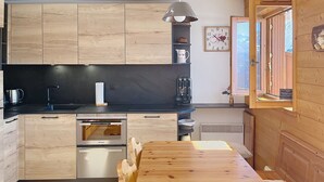A modern kitchen with wooden cabinets, a built-in oven, and a dining area with a wooden table and chairs.