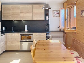 Uma cozinha moderna com armários de madeira, forno embutido e área de jantar com mesa e cadeiras de madeira.