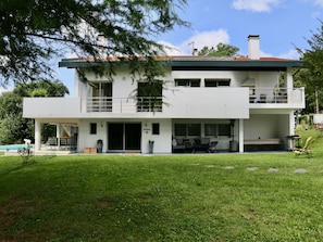 Une maison moderne à deux étages, dotée d’un toit plat, de grandes fenêtres et d’un balcon.