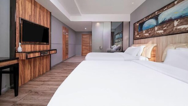 A modern hotel room with a large bed, a flat-screen TV mounted on a wooden panel, and a large abstract painting on the wall. - Nanning Unitour Hotel (Nanning)