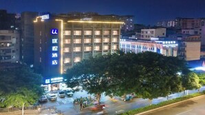 A hotel with multiple floors, illuminated signage, and a parking area with cars. - Nanning Unitour Hotel (Nanning)