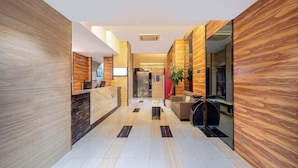 A modern hotel lobby with a reception desk, seating area, and a large mirror. - Nanning Unitour Hotel (Nanning)