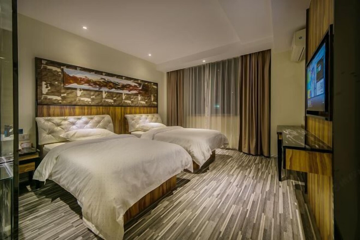 A hotel room with two beds, a large painting on the wall, a TV, and a wooden cabinet.