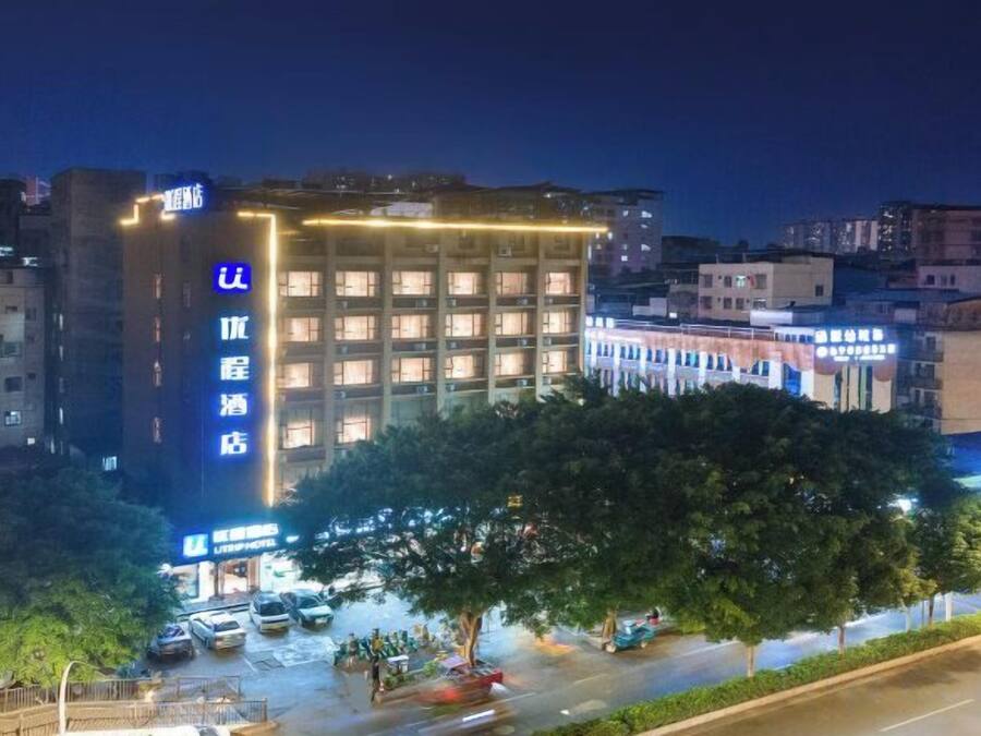 Un hotel de varios pisos con una entrada destacada, estacionamiento y vista a la calle.