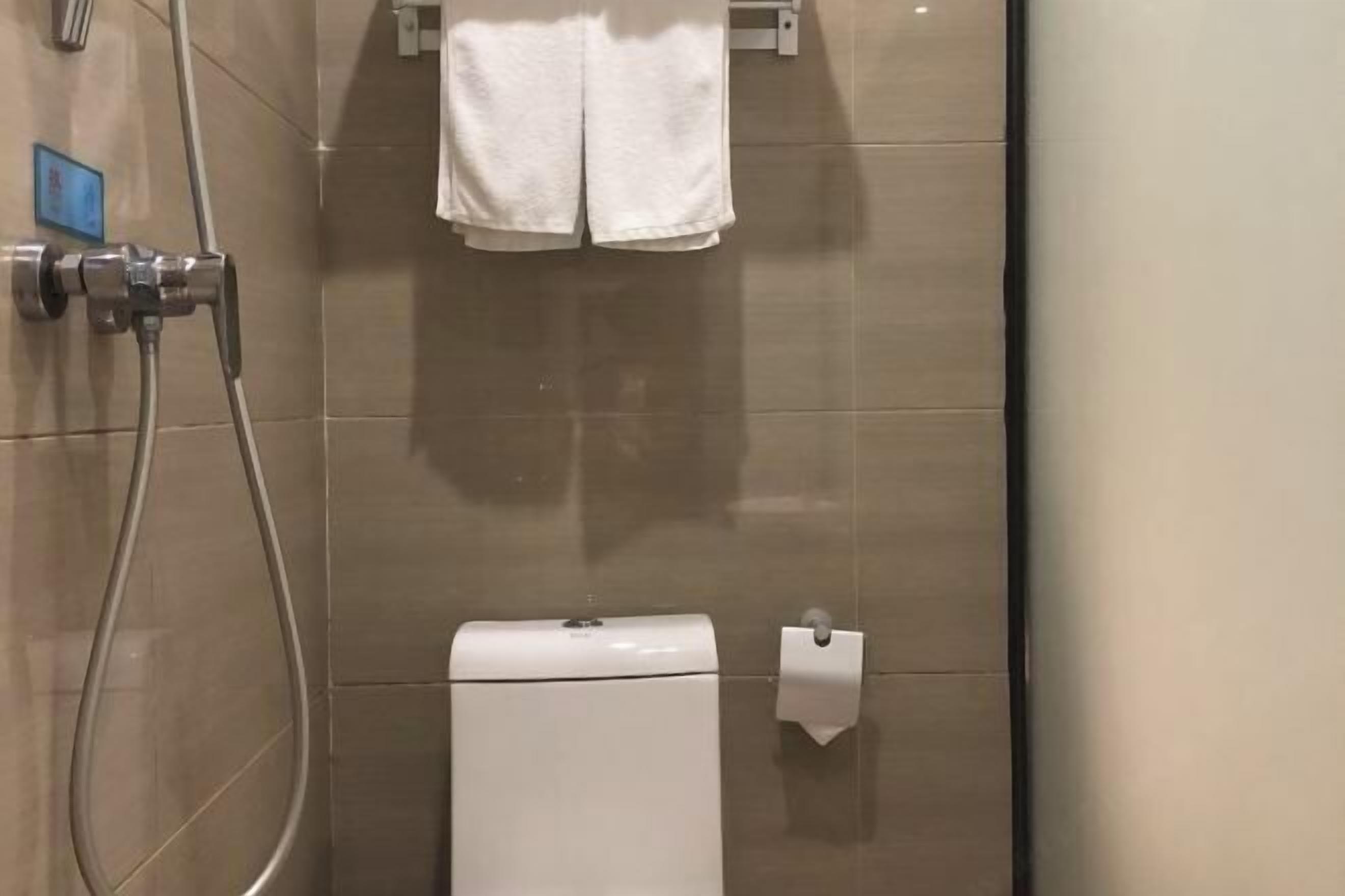 Een badkamer met toilet, een handdoekhouder en een papieren handdoekdispenser.