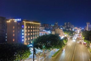 A cityscape at night with illuminated buildings, a multi-story hotel with a sign, and a busy street with vehicles. - Nanning Unitour Hotel (Nanning)
