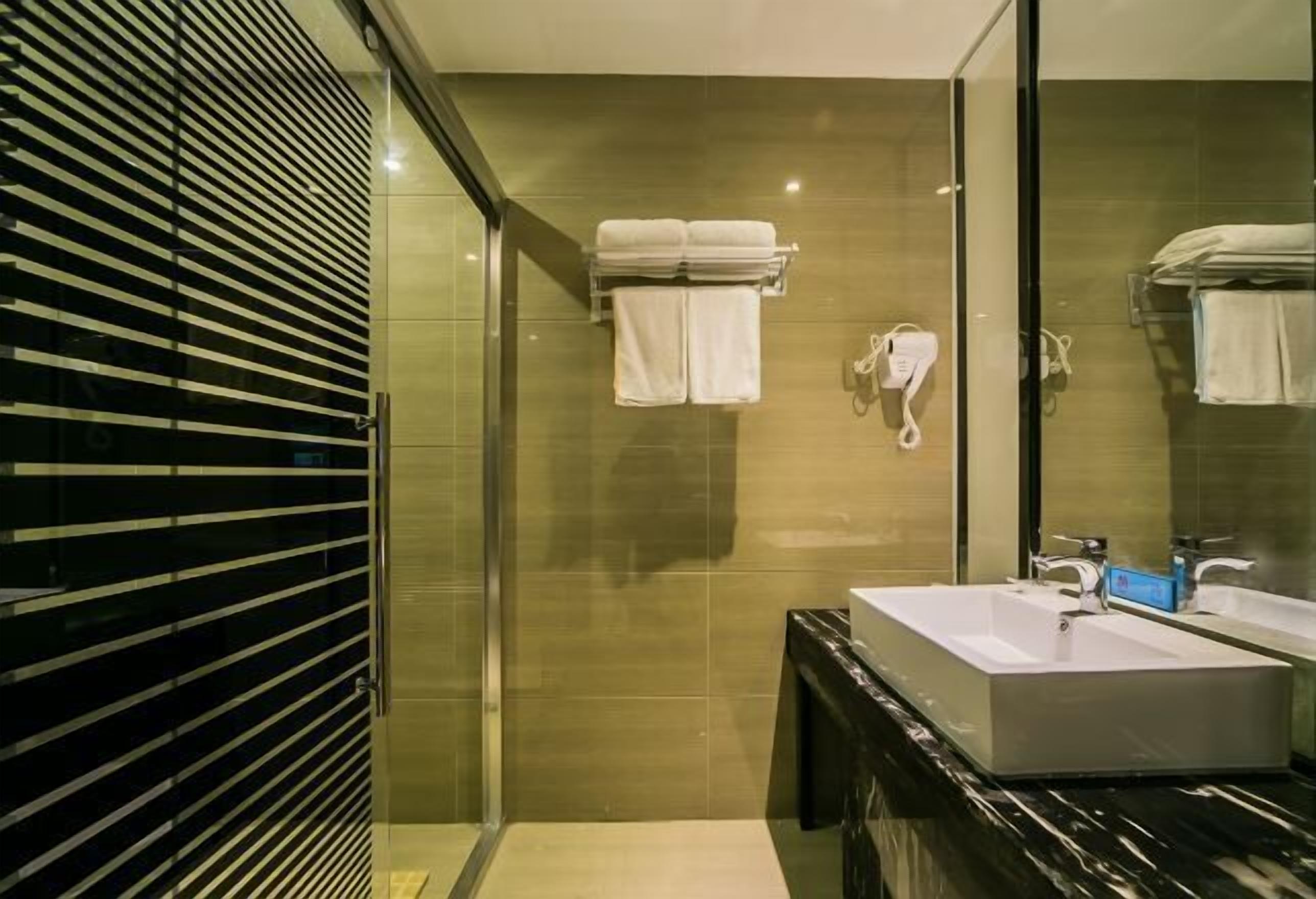 A modern bathroom with a large mirror, a rectangular sink, and a glass shower enclosure.