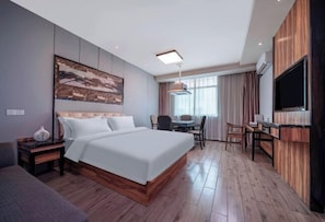 A modern hotel room with a large bed, a dining area, and a TV mounted on the wall. - Nanning Unitour Hotel (Nanning)