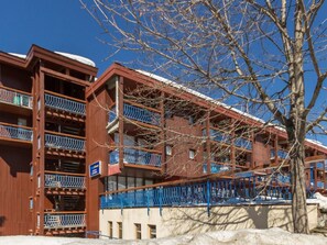Um edifício de vários andares com varandas e cerca azul.