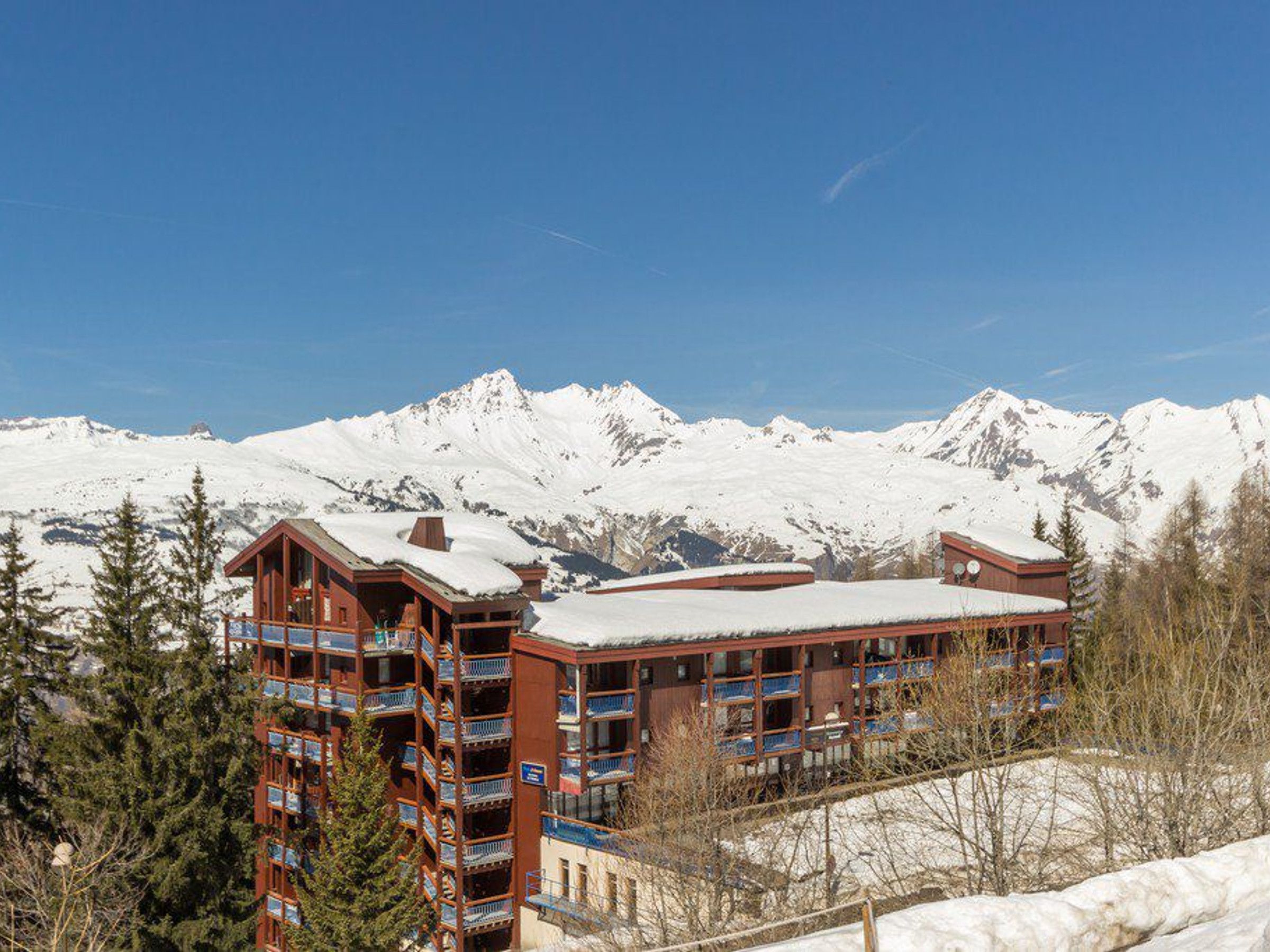Ein mehrstöckiges Hotel mit Balkonen und einem schneebedeckten Berg im Hintergrund.