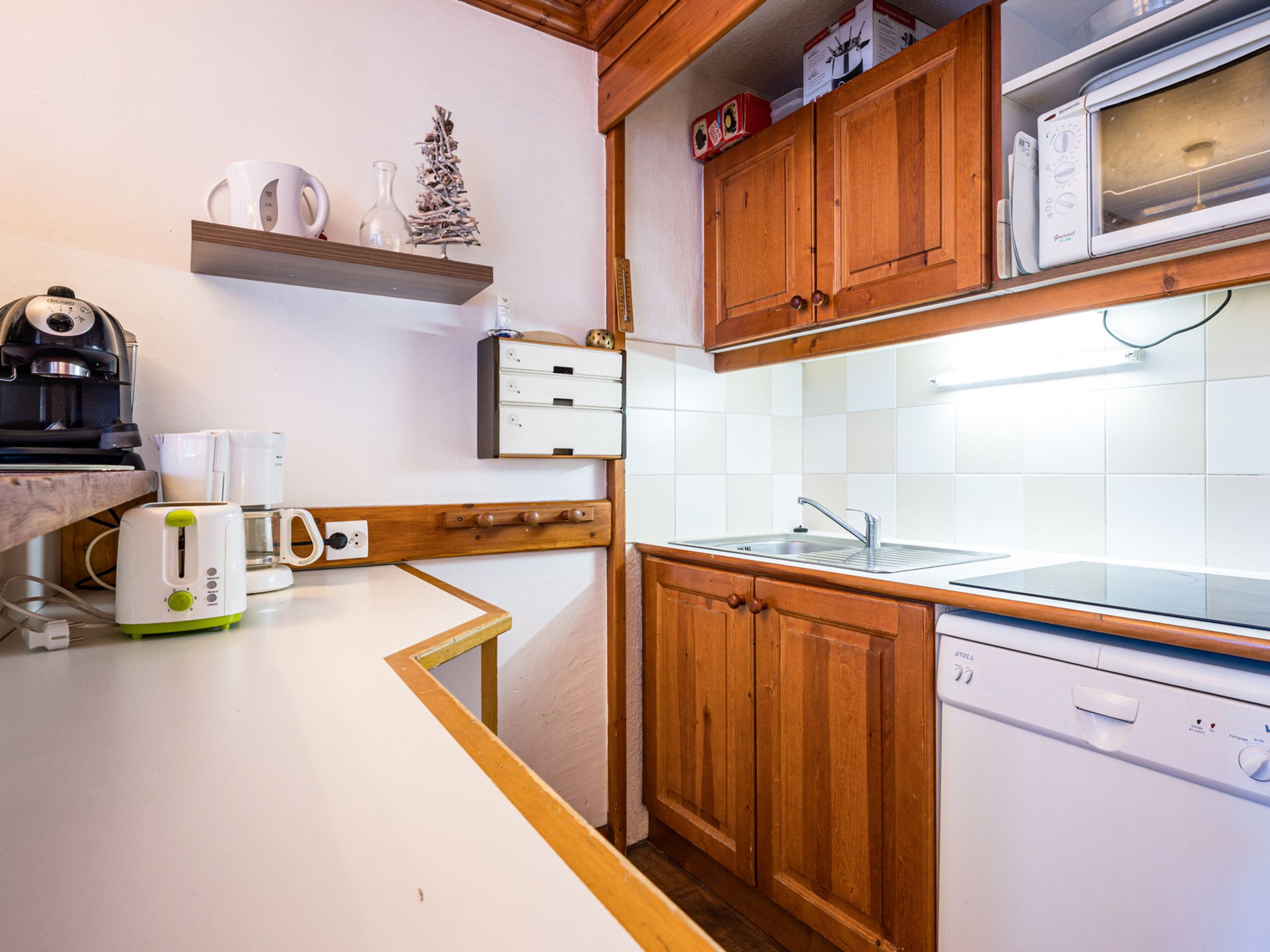A compact kitchen with wooden cabinets, a microwave, a toaster, and a coffee maker.