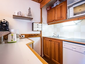 A compact kitchen with wooden cabinets, a microwave, a toaster, and a coffee maker.