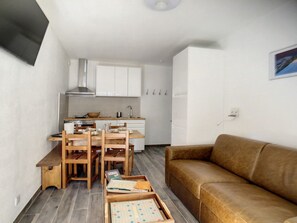 A compact living space with a kitchenette, a dining area with wooden furniture, and a brown sofa. - Renovated Apartment in Les Menuires, 4 pers, near slopes (Les Menuires)