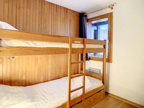 A bunk bed room with wooden walls and a window.