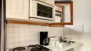 Eine kleine Küche mit Herd, Mikrowelle, Kaffeemaschine und Geschirrspüler.