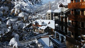 Ein verschneites Bergdorf mit traditionellen Holzhäusern und einem markanten Kirchturm.