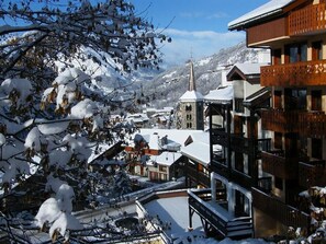 A snow-covered mountain village with traditional wooden buildings and a prominent church steeple.