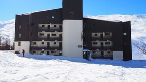 A modern multi-story building with a flat roof, surrounded by snow.