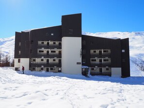 A modern multi-story building with a flat roof, surrounded by snow.