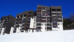 A multi-story hotel with balconies and a ski slope in the background.