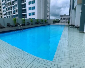 A swimming pool with tiled flooring and lounge chairs. - Modern loft-style, 2 level apartment  with city views, cover parking and pool.   (Panamá)