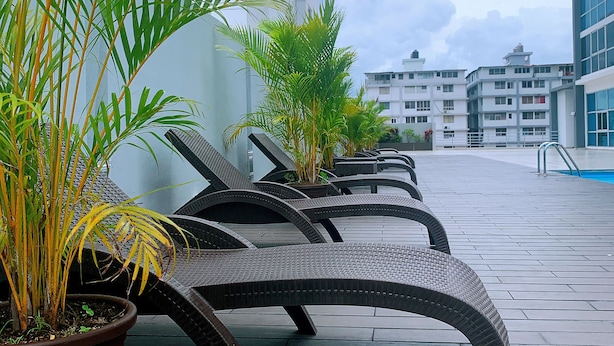 Udendørs siddepladser med plantekasser, fliseterrasse og moderne bygninger i baggrunden.