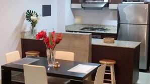 Et moderne køkken med spiseplads, inklusive et bord med stole, en vase med blomster og en mikrobølgeovn over køkkenbordet.