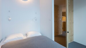 Un dormitorio minimalista con una cama, lámparas de noche y una puerta de madera.