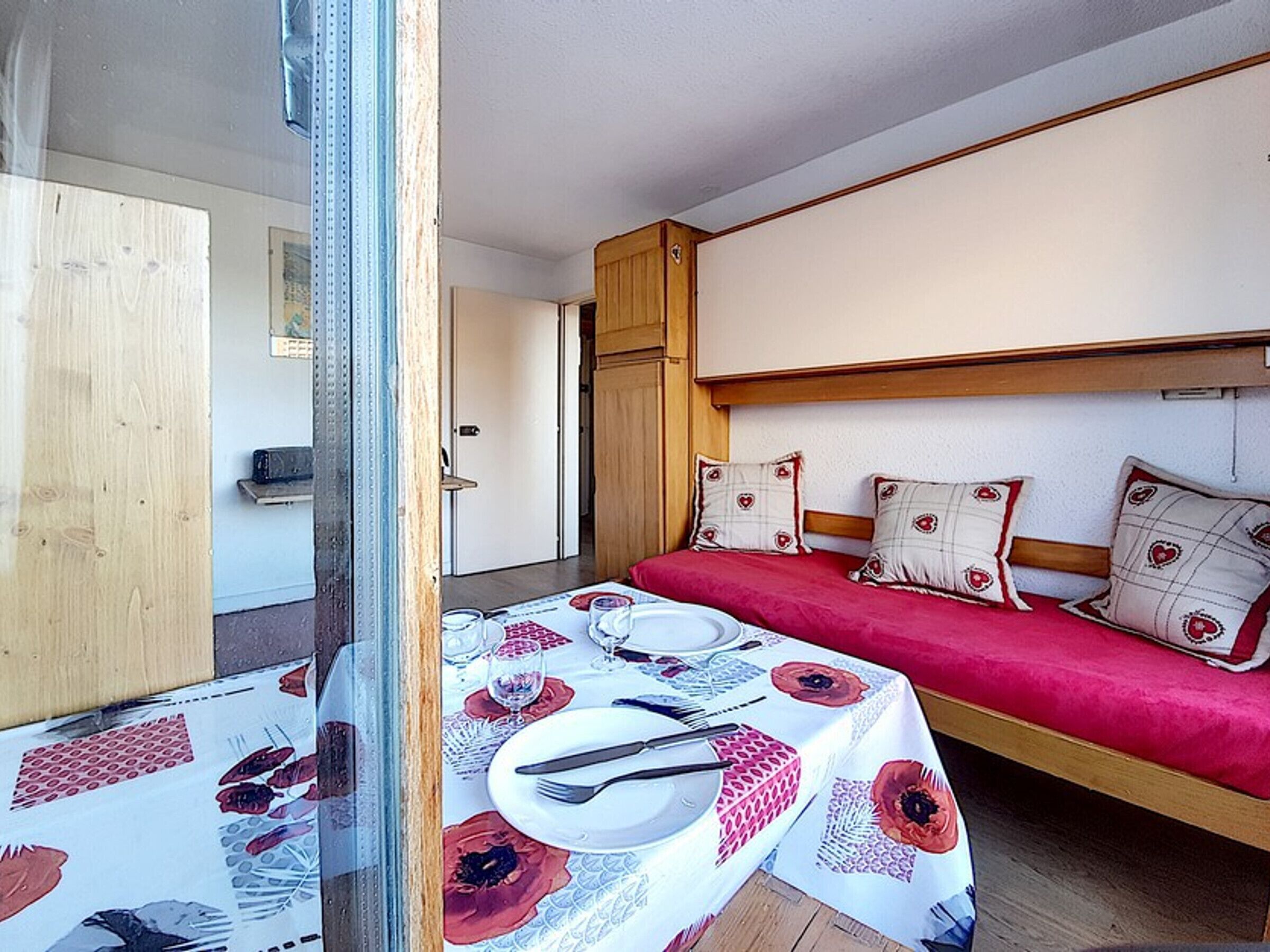 Una habitación con una cama, una mesa preparada para dos comensales y una puerta de madera.