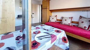 Una habitación con una cama, una mesa preparada para dos comensales y una puerta de madera.
