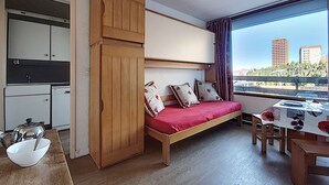 Una habitación compacta con cama, una kitchenette pequeña y un comedor.