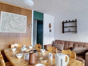 Un comedor con mesa de madera, sillas y distintos utensilios de mesa.
