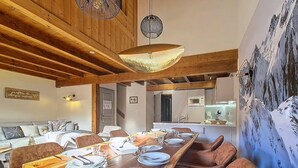 Un coin repas avec une table en bois dressée pour quatre personnes, entourée de chaises en cuir.