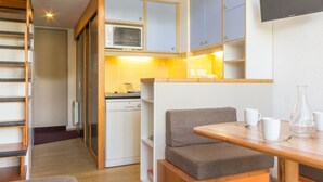 Une cuisine compacte équipée d’un four à micro-ondes, d’un évier et d’un petit coin repas avec un banc et une table.