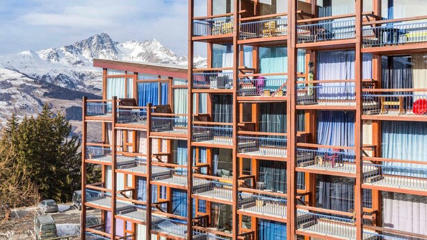 A multi-story hotel with balconies, set against a mountainous backdrop. - Cabin studio for 4, balcony, south facing, Les Arcs 1800 (Les Arcs 1800)