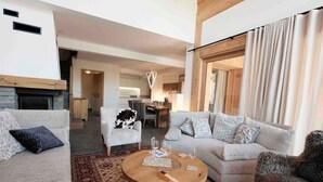 Ein modernes Wohnzimmer mit einem runden Couchtisch, zwei Sofas, einem gemusterten Teppich und einem Kamin.