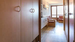 Un couloir doté de meubles en bois, un petit coin salon avec un canapé et des fauteuils, et une grande fenêtre laissant entrer la lumière naturelle.