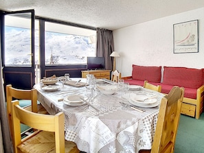 Ein Essbereich mit einem Tisch für vier Personen, einem Fernseher und einer Couch.