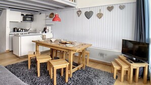 A compact living space with a dining area, kitchenette, and a TV.