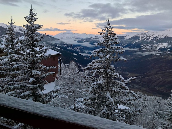 A mountain view with snow-covered trees and a building in the foreground.