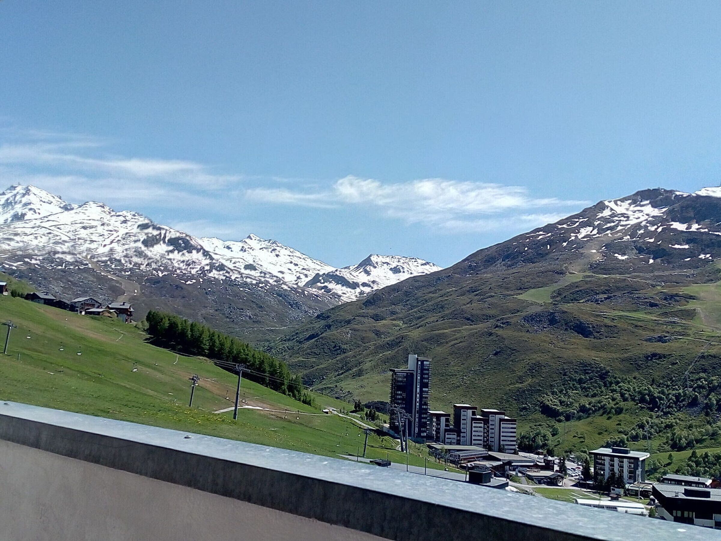 Un paysage montagneux aux sommets enneigés, avec une petite ville dotée de bâtiments modernes et d’une station de ski.