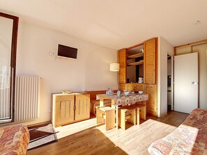 Un espacio habitable compacto con kitchenette, comedor y una pequeña zona de estar.