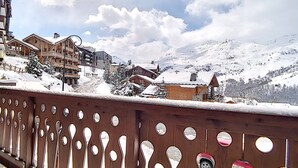 A snow-covered mountain landscape with wooden buildings and a wooden fence with circular cutouts.