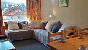 A cozy room with a bed, a wooden table with a cup, and a window with curtains. - 2-Room Apartment · Balcony · Free Wifi (Les Arcs 1800)