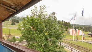 A balcony with a view of a tree, a railway track, and flags. - 2-Room Apartment · Balcony · Free Wifi (Les Arcs 1800)